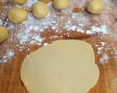 Step <p>Volcamos el contenido del vaso encima de una tabla de trabajar , formamos bolas del tamaño de una nuez. estiramos con un rodillo cada bola dando forma de circulo (aprox.cm14) y lo colocamos dentro de los flamenquines Thermomix o otros moldes similares, por ej. moldes de silicona para madalenas</p> illustration